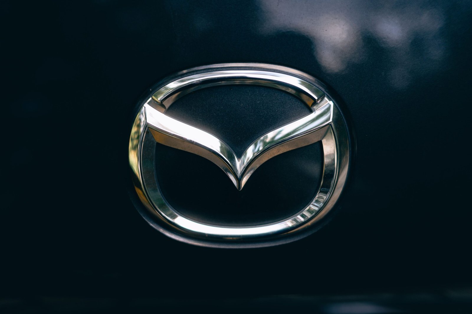 Home Close-up of a shiny metallic car logo on a dark surface.